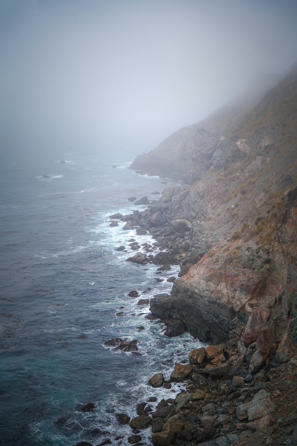 brown rocky mountain beside sea during daytime