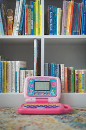 pink and white digital device on white wooden shelf