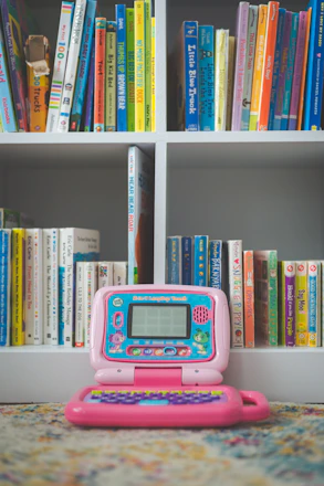 pink and white digital device on white wooden shelf