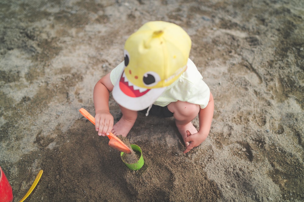 child in white shirt holding yellow plastic toy