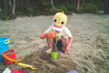 child in white shirt and shorts playing on sand during daytime