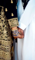 A mother and daughter holding hands, both wearing matching cultural outfits with intricate patterns.