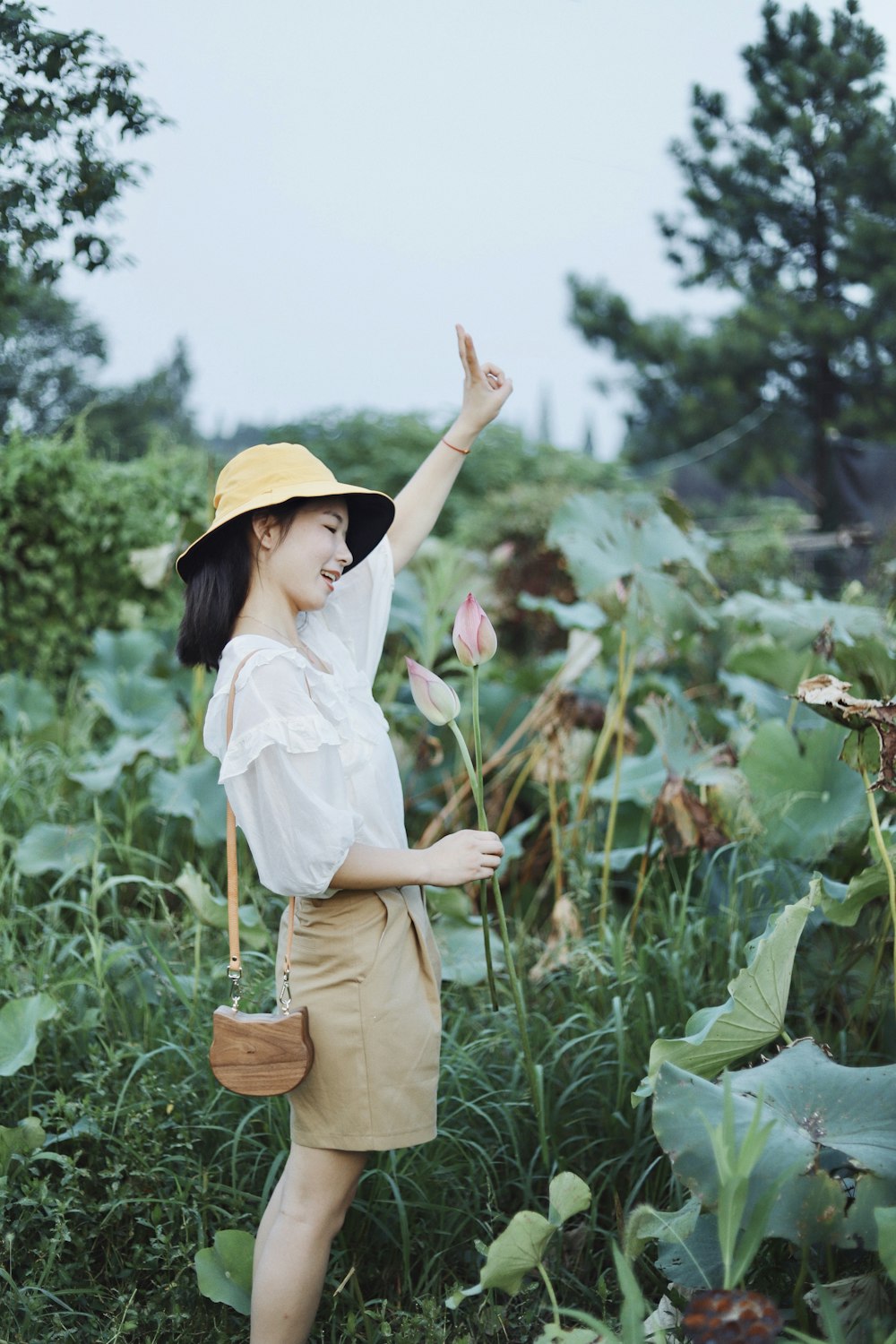 woman in white dress shirt and brown pants standing on green grass field during daytime