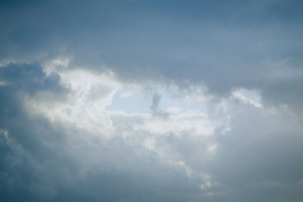 a plane flying through a cloudy blue sky