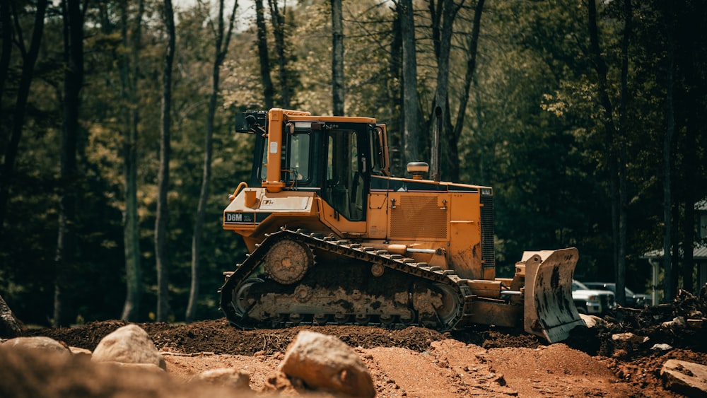 yellow and black front loader on forest during daytime