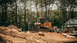 Close-up of a bulldozer clearing earth with dust rising in an industrial setting.