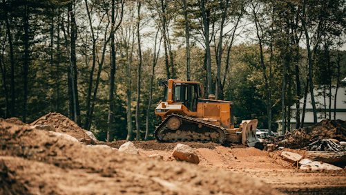 A bulldozer clearing land with a backdrop of vibrant African landscape and focused operators.
