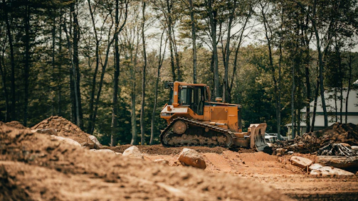 Close-up of a bulldozer clearing earth with dust rising in an industrial setting.