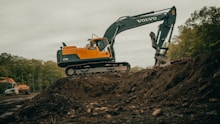 orange and white excavator on brown ground during daytime