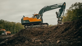 orange and white excavator on brown ground during daytime