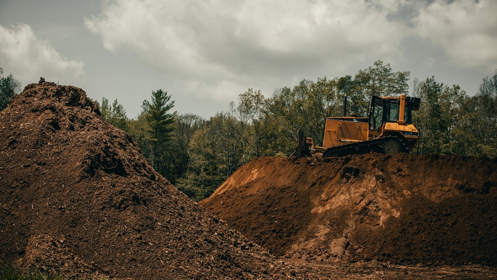 yellow and black heavy equipment on brown rocky hill under white cloudy sky during daytime