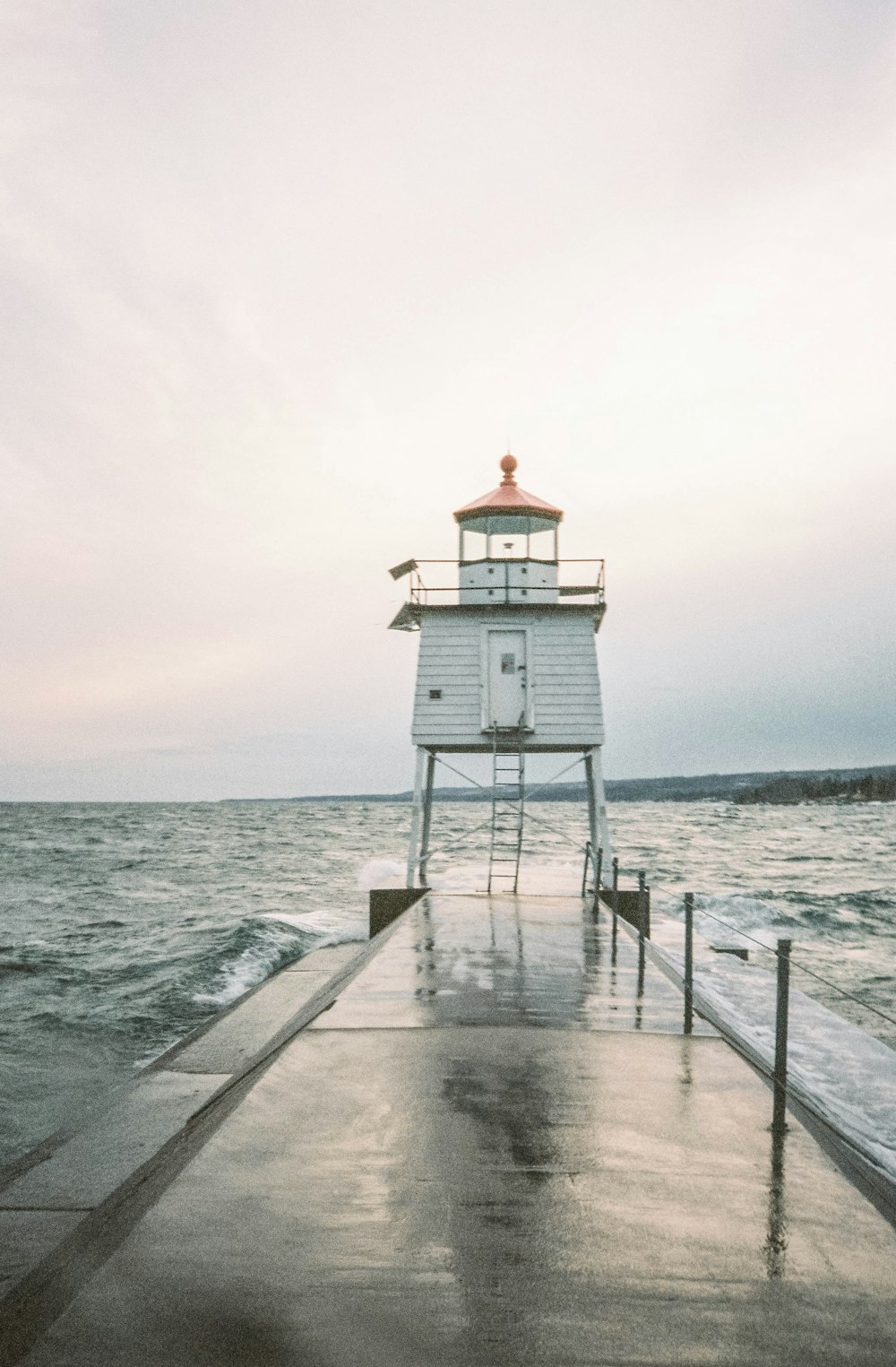 white and red wooden watch tower near sea during daytime