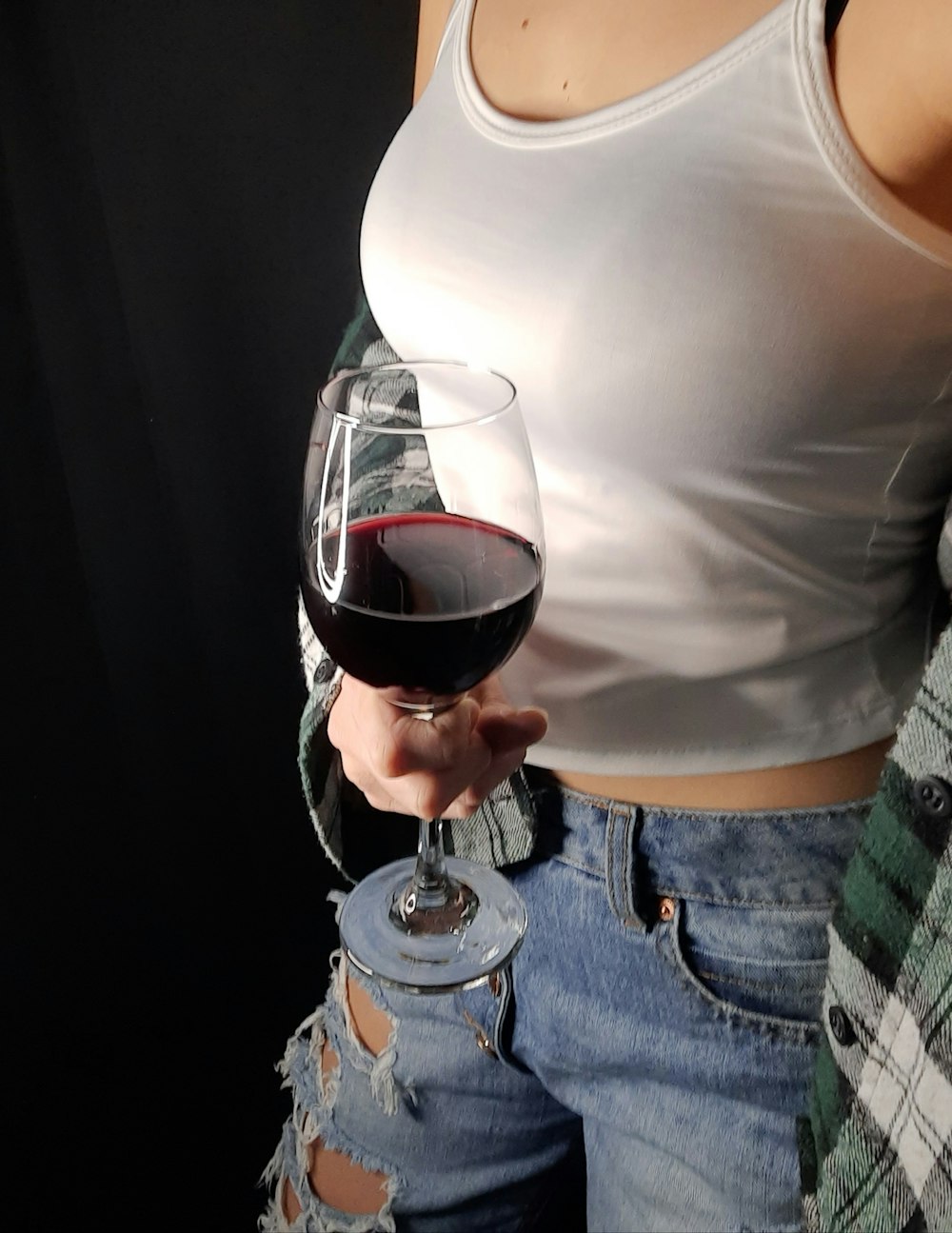 Mujer en camiseta blanca sin mangas sosteniendo una copa de vino