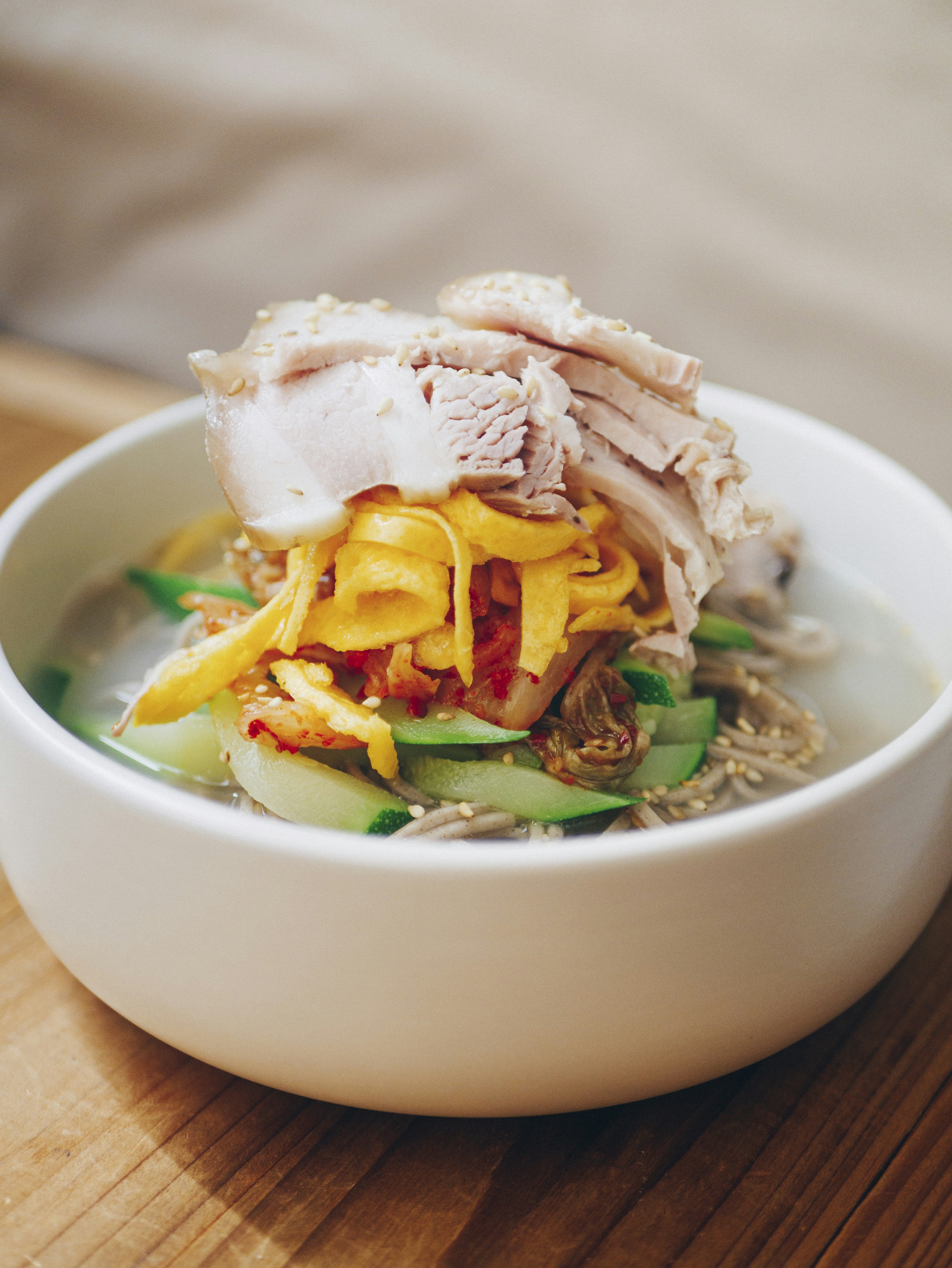 Korean ox bone soup seolleongtang in white bowl with rice noodles and green onions