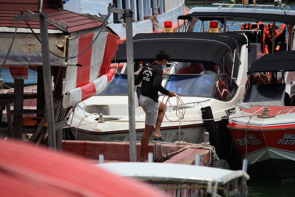 man in black jacket and blue denim jeans riding on white and red boat during daytime