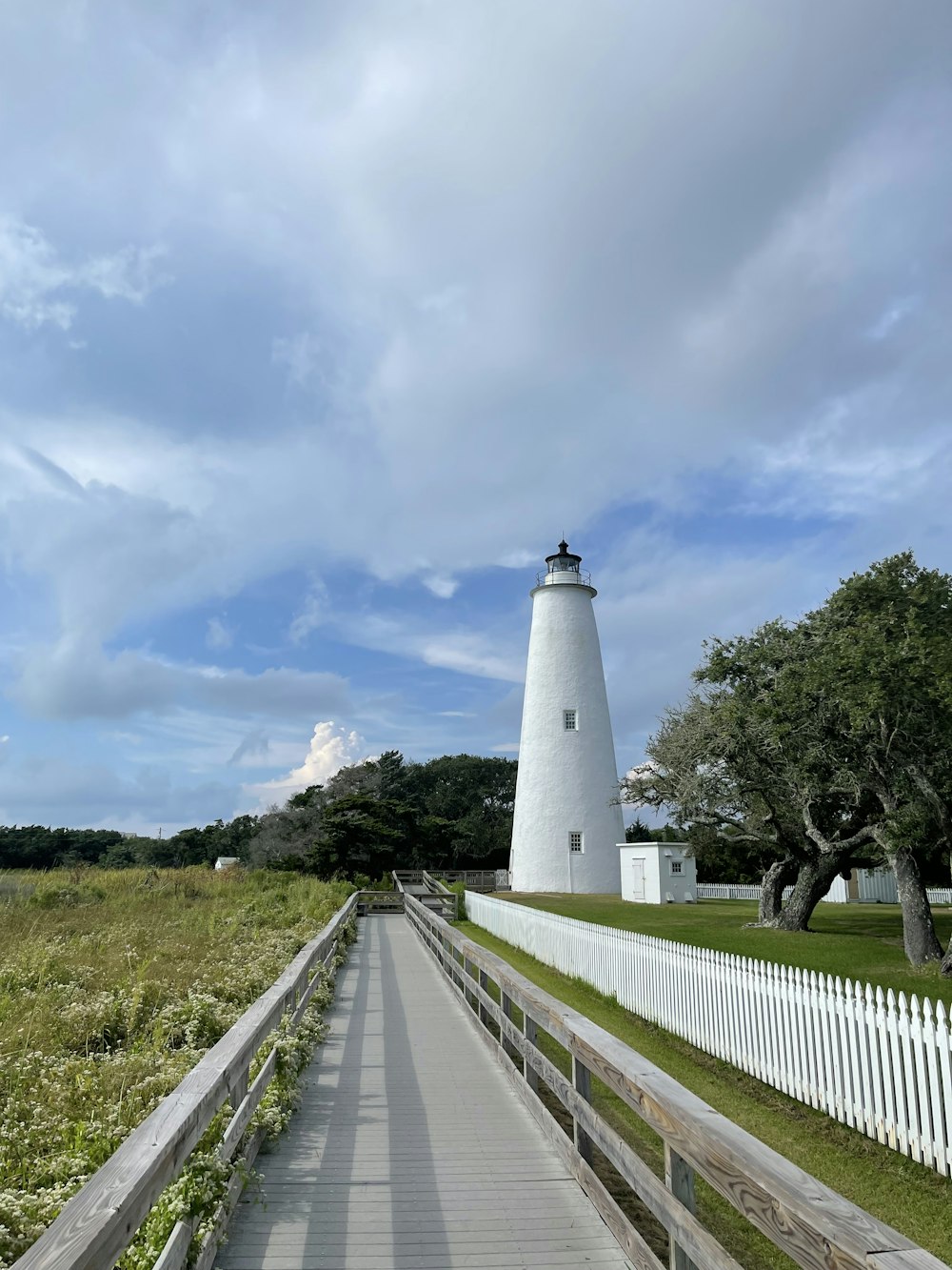 white and black lighthouse near green grass field under white clouds during daytime