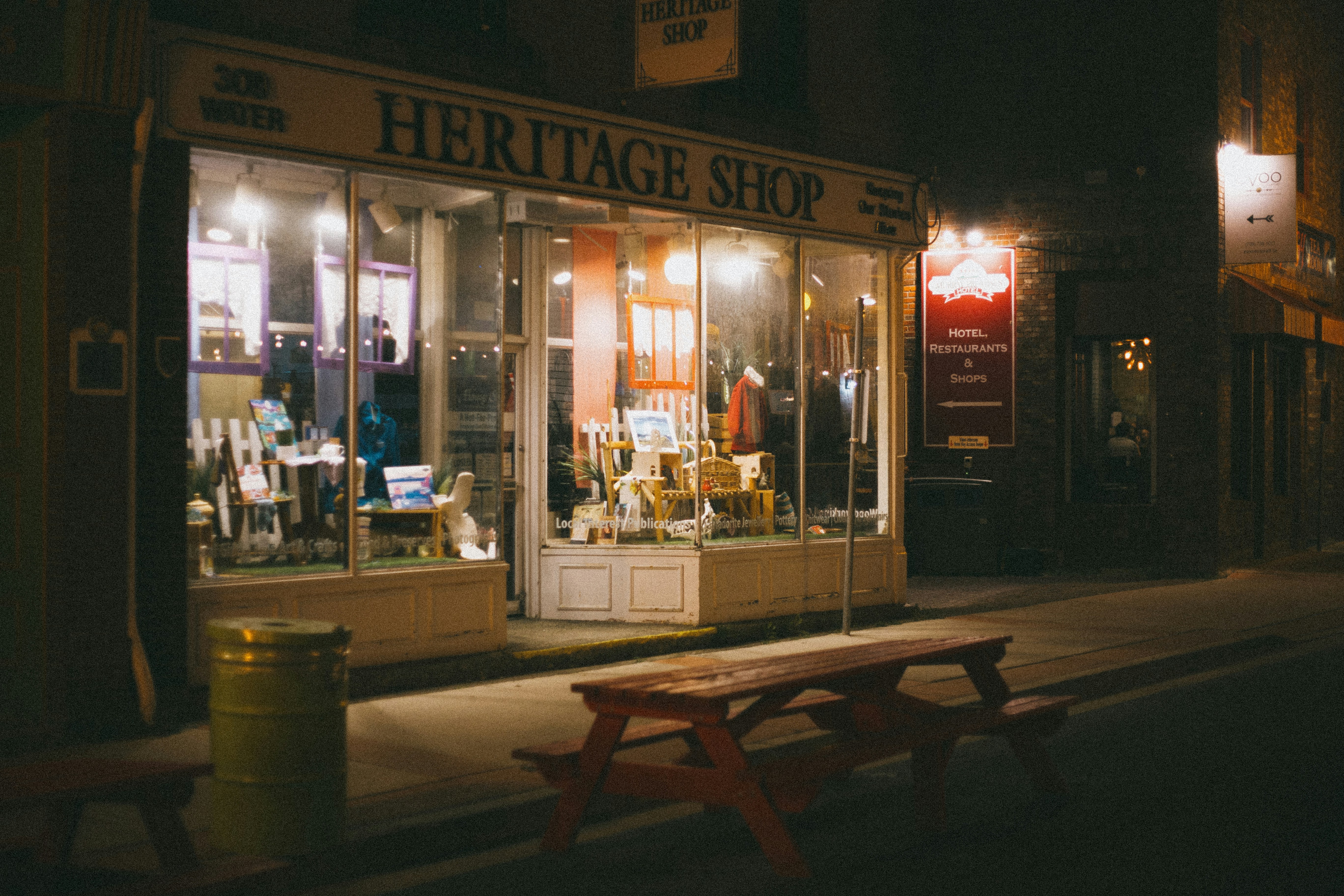 Heritage shopfronts lit at night with a bench