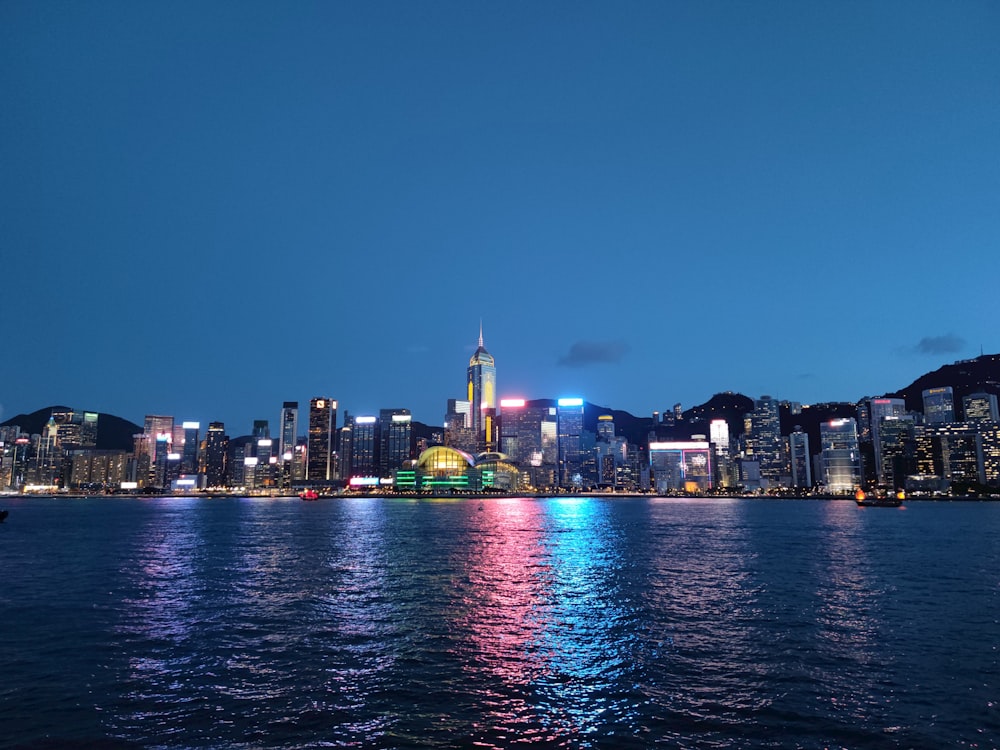 city skyline across body of water during night time