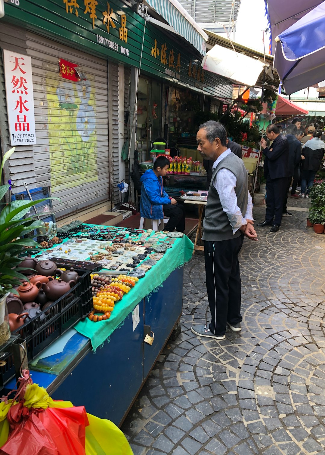man in white dress shirt and black pants standing near green vegetable stand during daytime