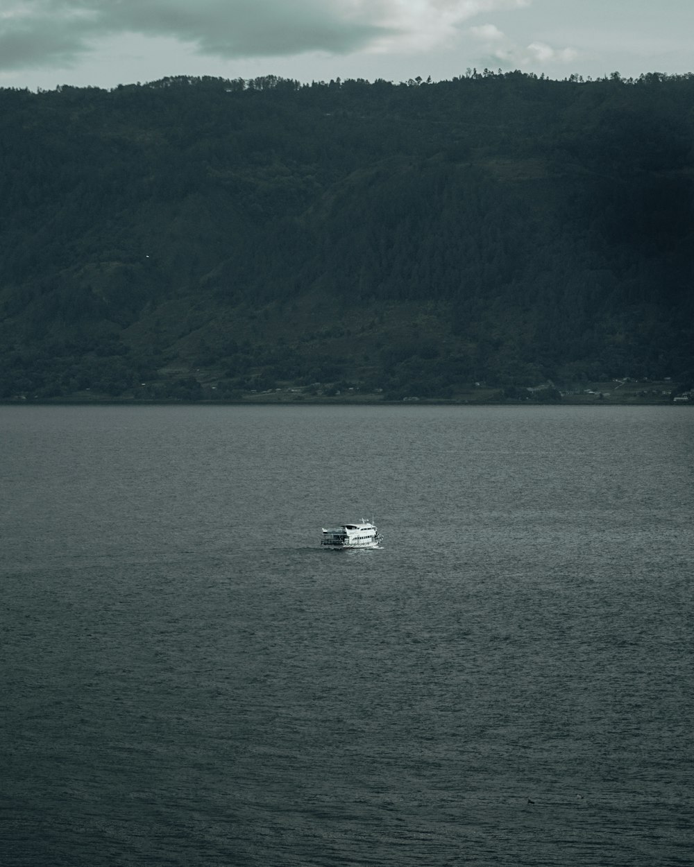 white boat on sea near mountain during daytime