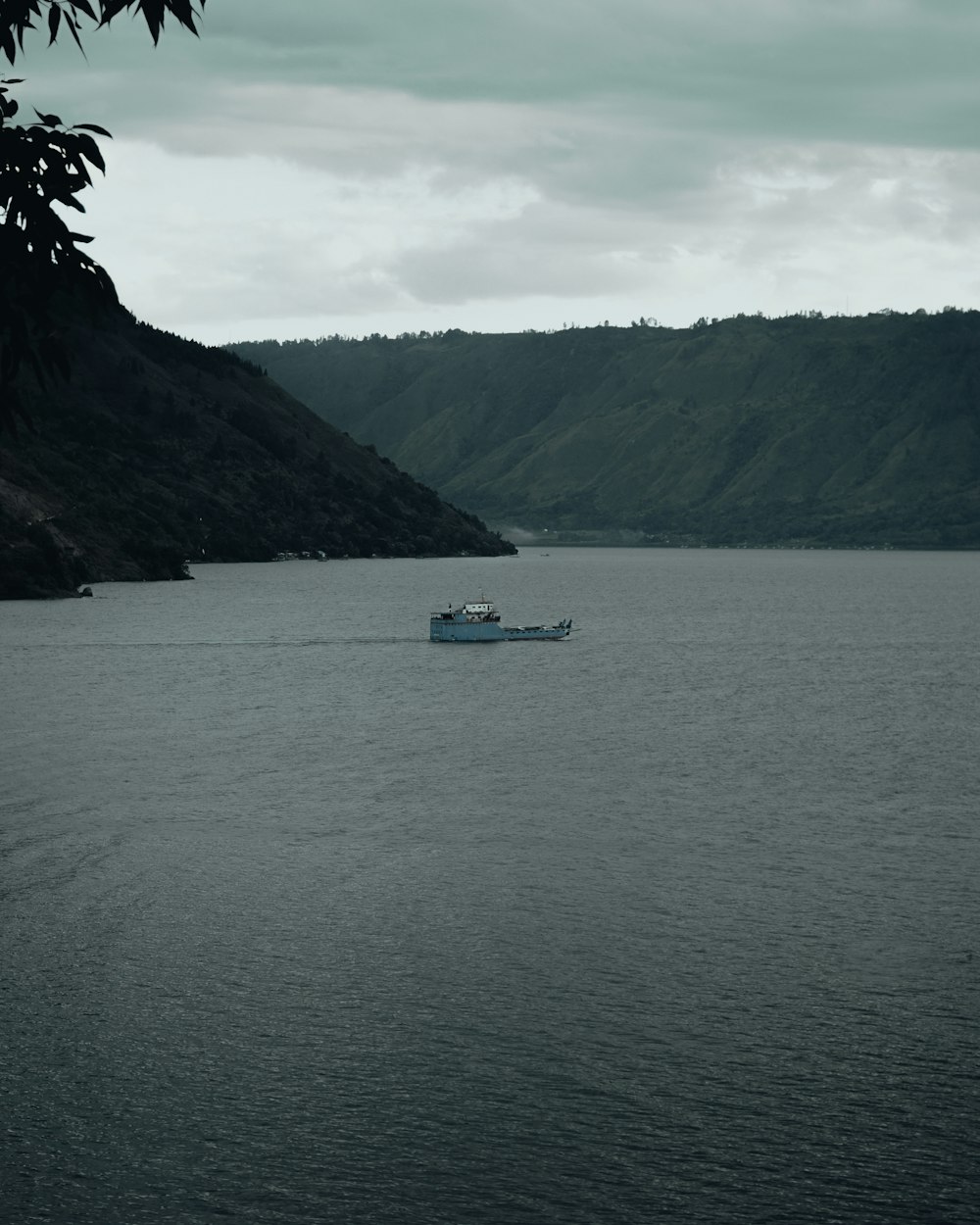 white boat on body of water near mountain during daytime