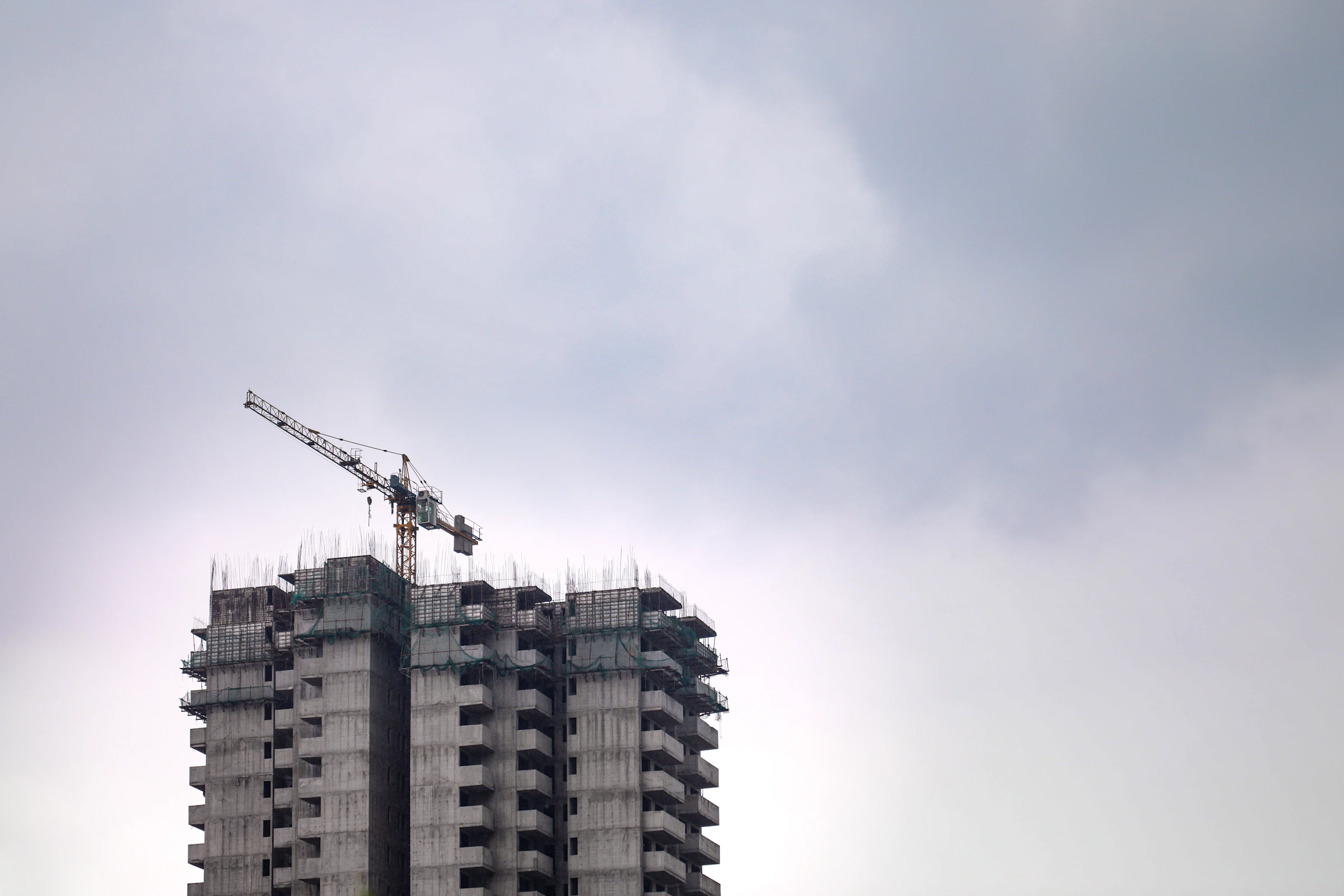 Betonrohbau mit Baukran unter hellem Himmel