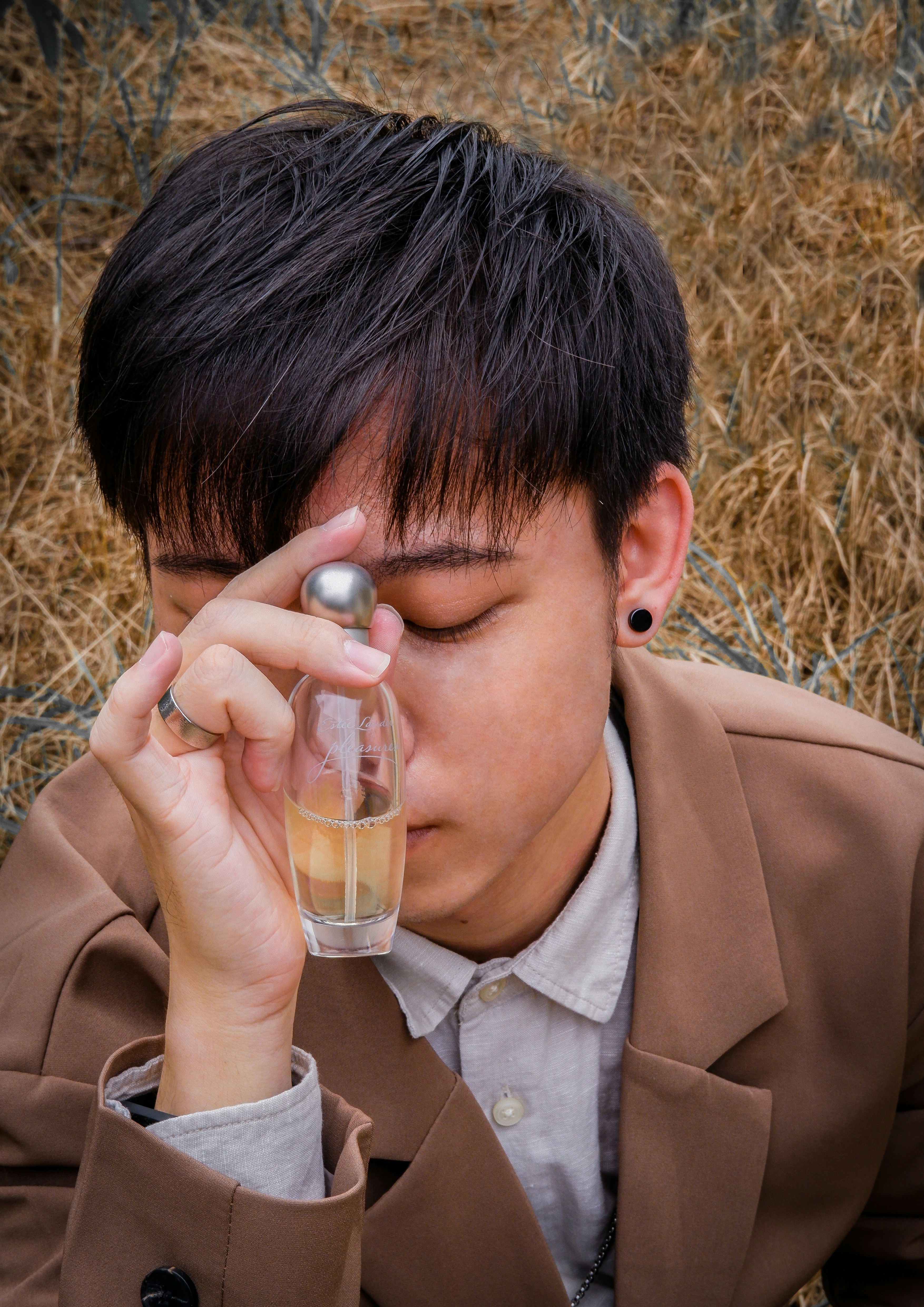 man in brown suit jacket holding clear glass mug