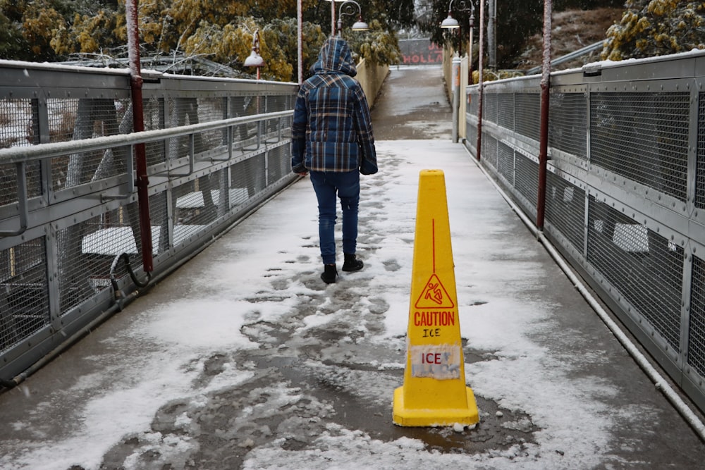 man in blue and white plaid dress shirt and blue denim jeans standing on bridge during