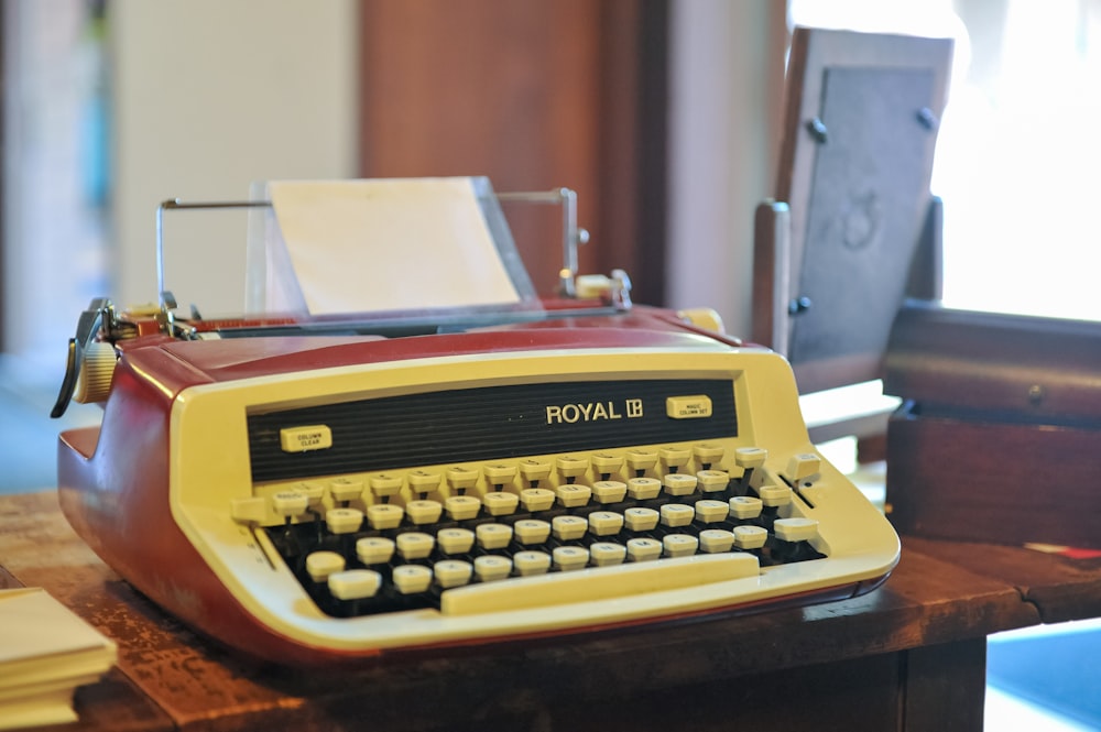 orange and white typewriter on brown wooden table