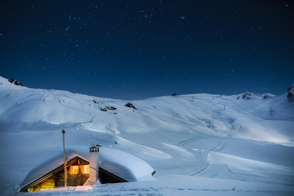 casa de madeira marrom na montanha coberta de neve durante a noite