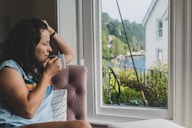a woman sitting in a chair looking out a window