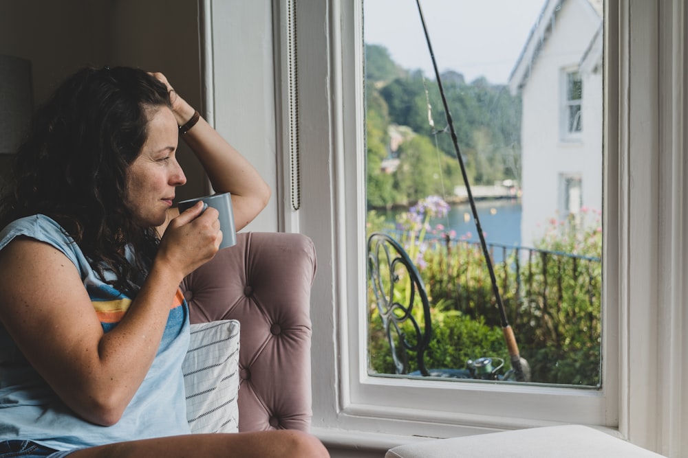 a woman sitting in a chair looking out a window