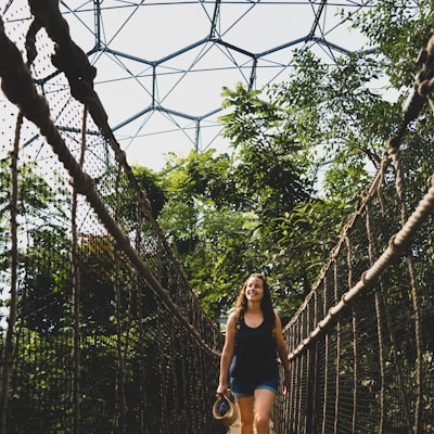 woman in black tank top and black shorts standing on hanging bridge during daytime