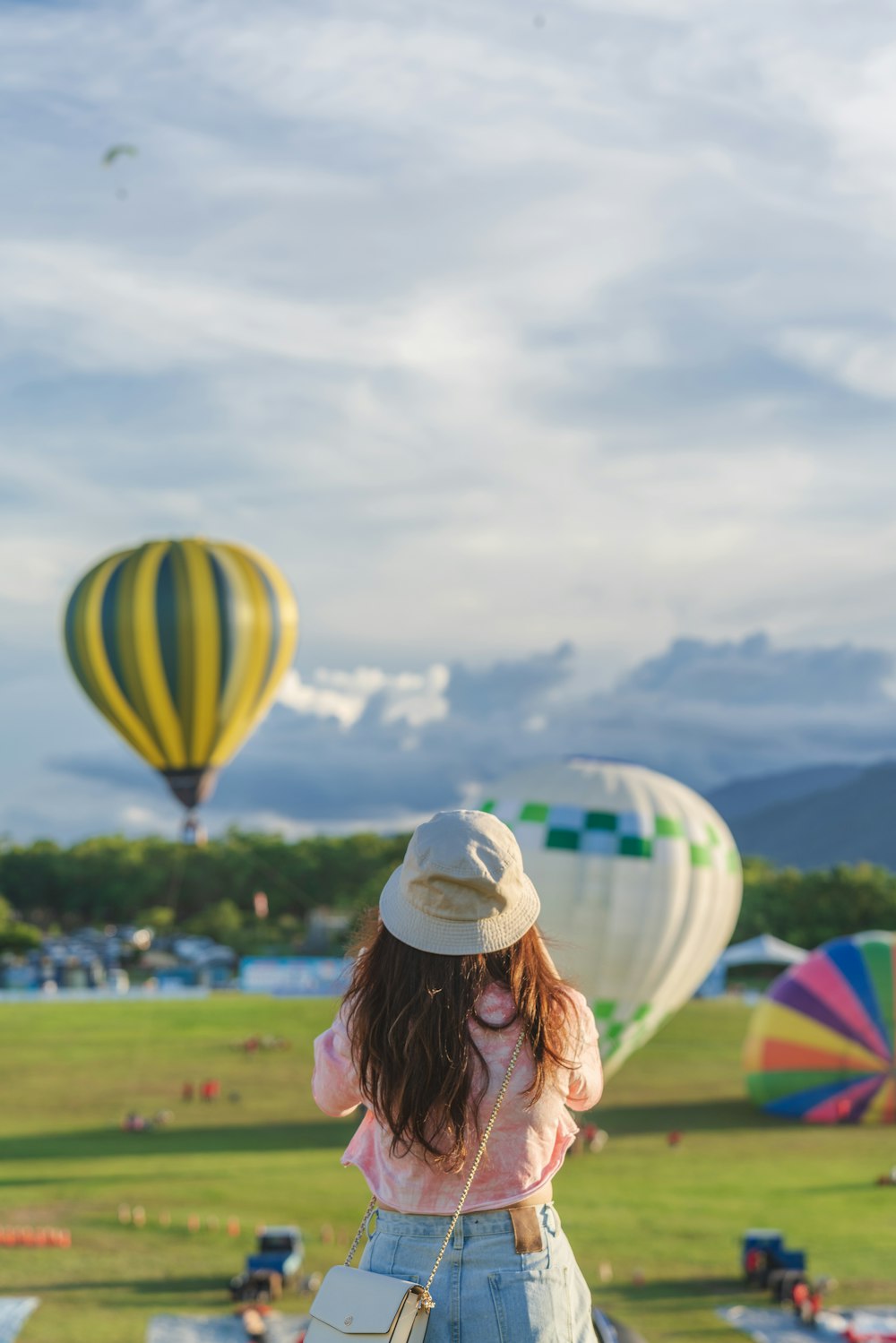 woman in white sun hat holding yellow green and blue hot air balloon