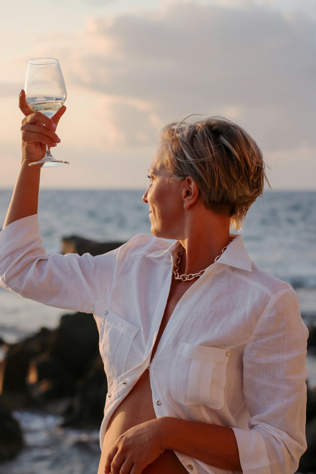 woman in white dress shirt holding clear drinking glass