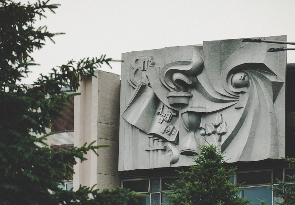 人間の顔が浮き彫りにされた灰色のコンクリートの建物