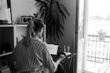 Black-and-white photo of Kushi Gurram working on a laptop in a minimalist workspace.