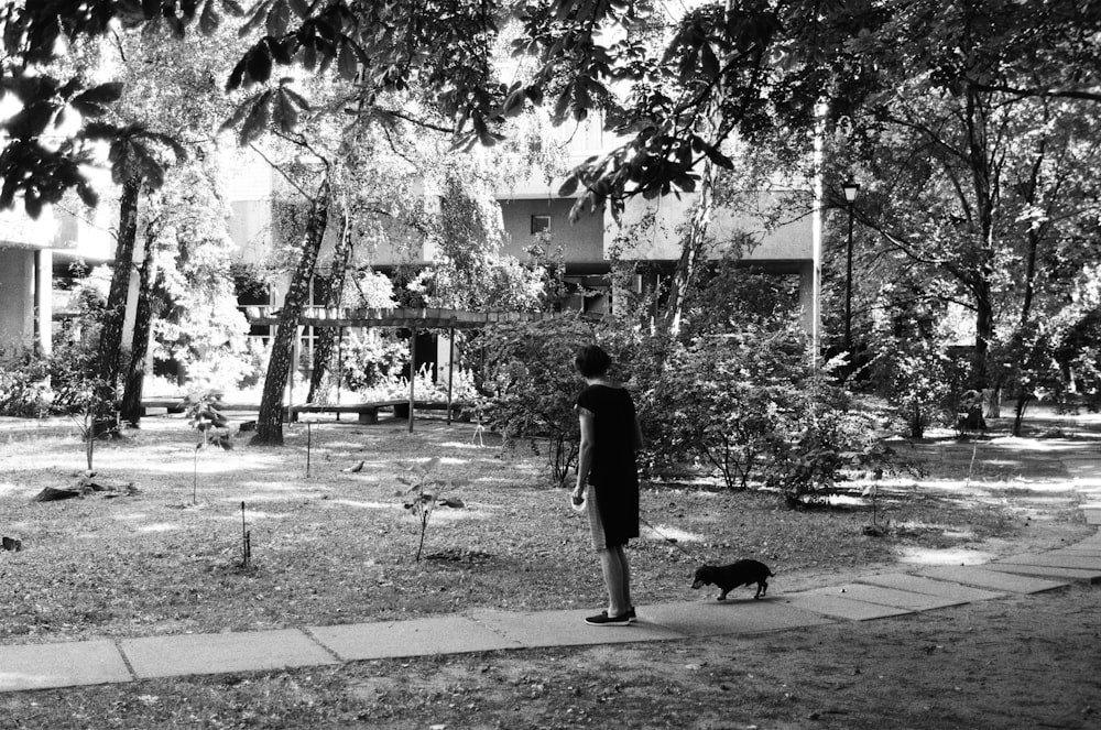 man in black shirt walking on sidewalk in grayscale photography