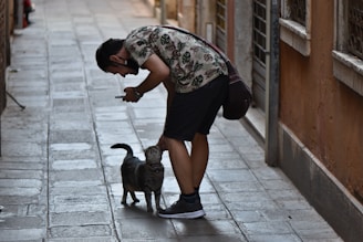 man in black t-shirt and black shorts holding black short coated dog