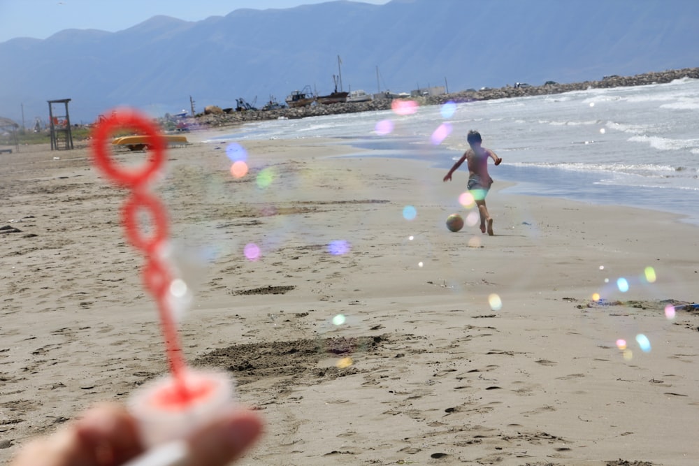 man in white shirt playing with bubbles on beach during daytime