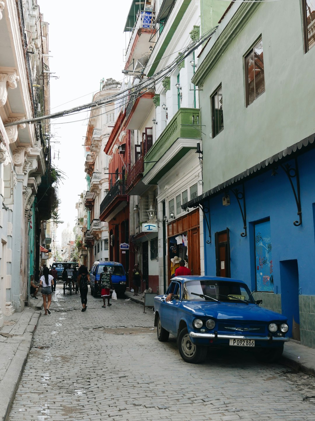 blue car parked beside blue building during daytime