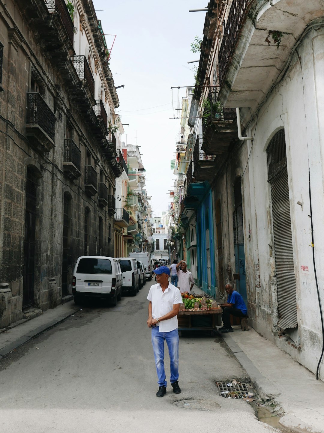 man in white t-shirt and blue denim jeans walking on sidewalk during daytime
