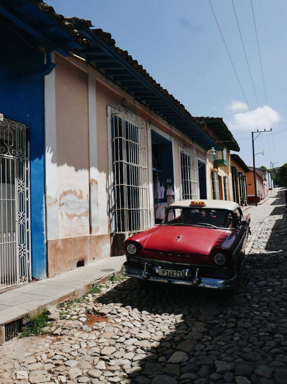 red car parked beside blue and white concrete building during daytime