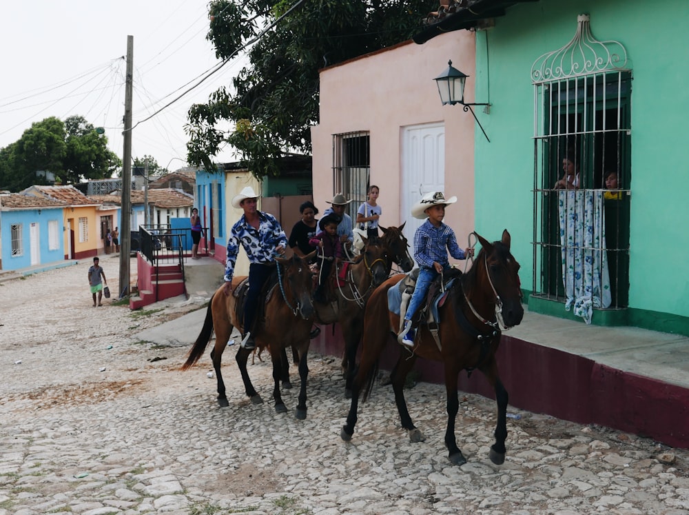 people riding horses on road during daytime