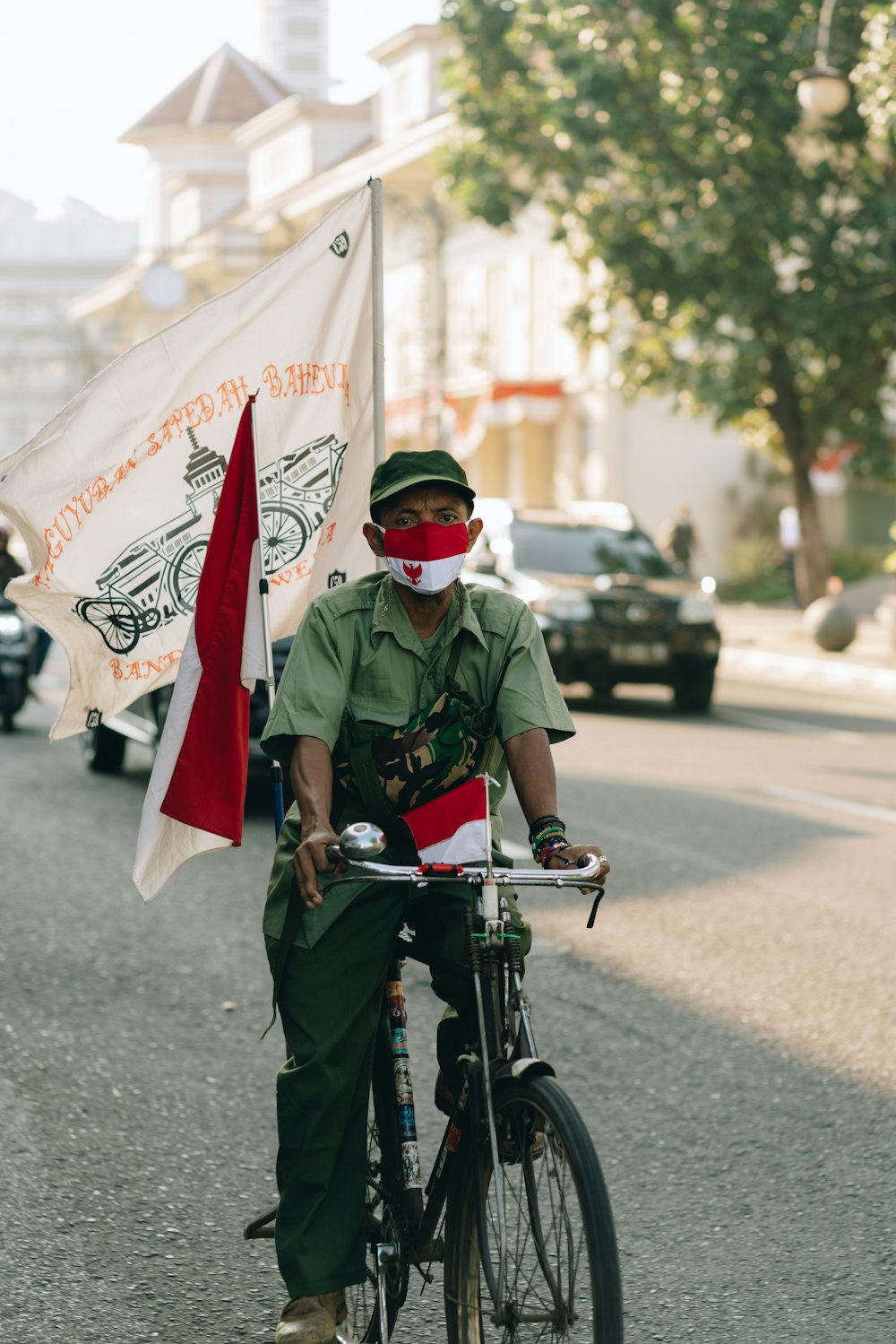 man in green and black camouflage uniform riding bicycle on road during daytime