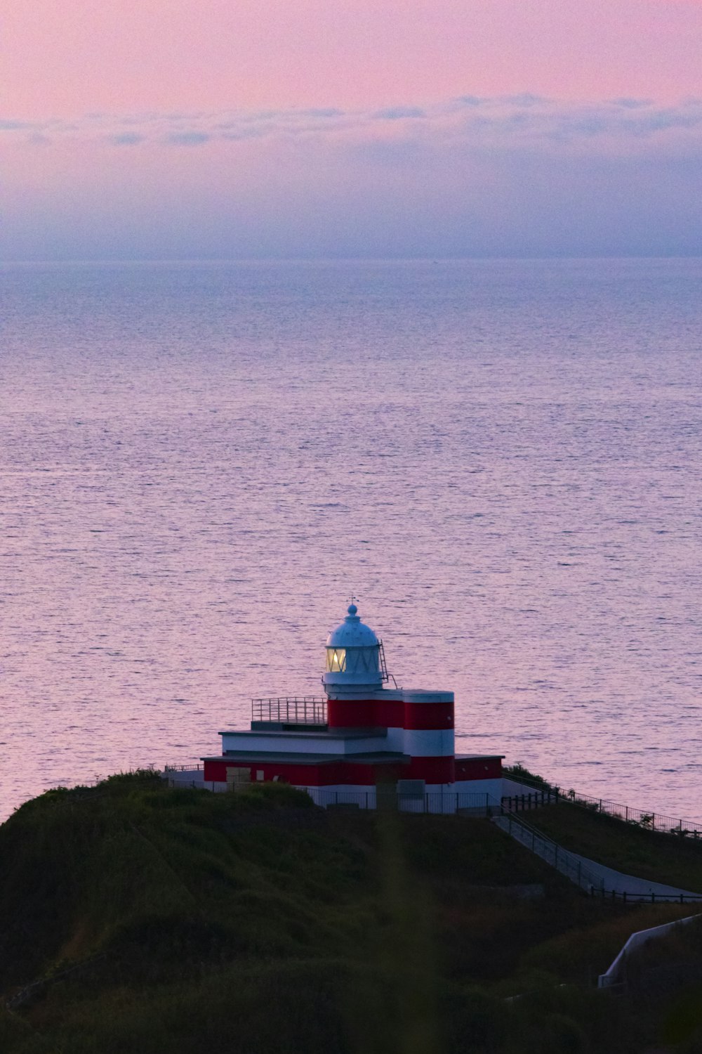 farol branco e vermelho perto do corpo de água durante o dia