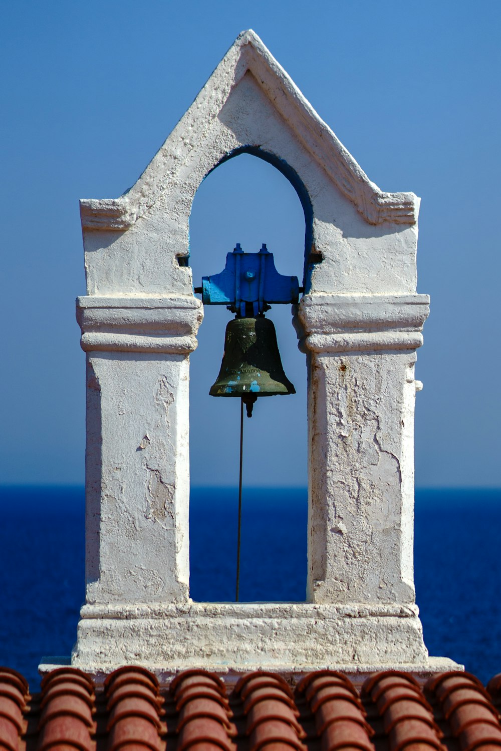 a bell on top of a building near the ocean