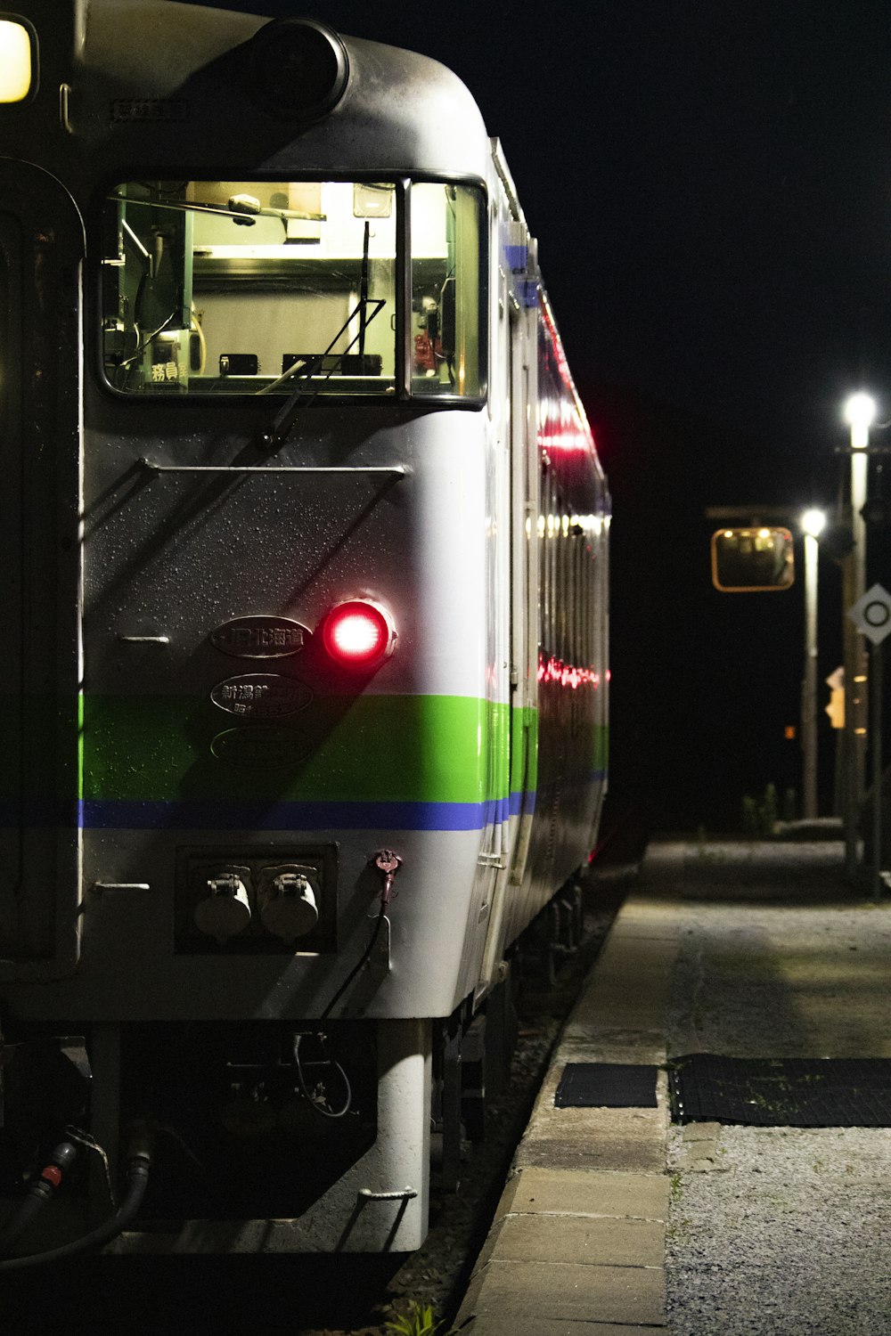 夜間の線路上の緑、白、赤の列車