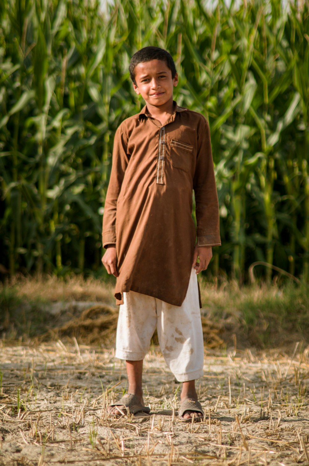 man in brown jacket and white shorts standing on brown grass field during daytime