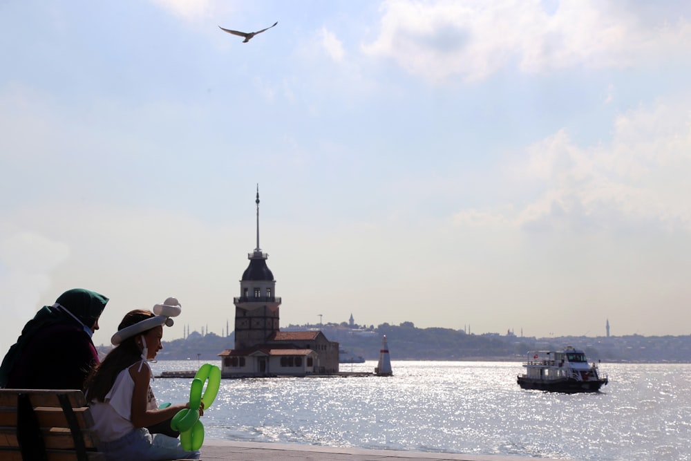 man in green shirt and brown hat sitting on green plastic chair near body of water